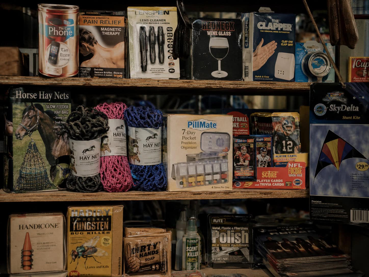 Shelf of oddly specific niche products including a tin-can phone, pill organizer, and trading cards