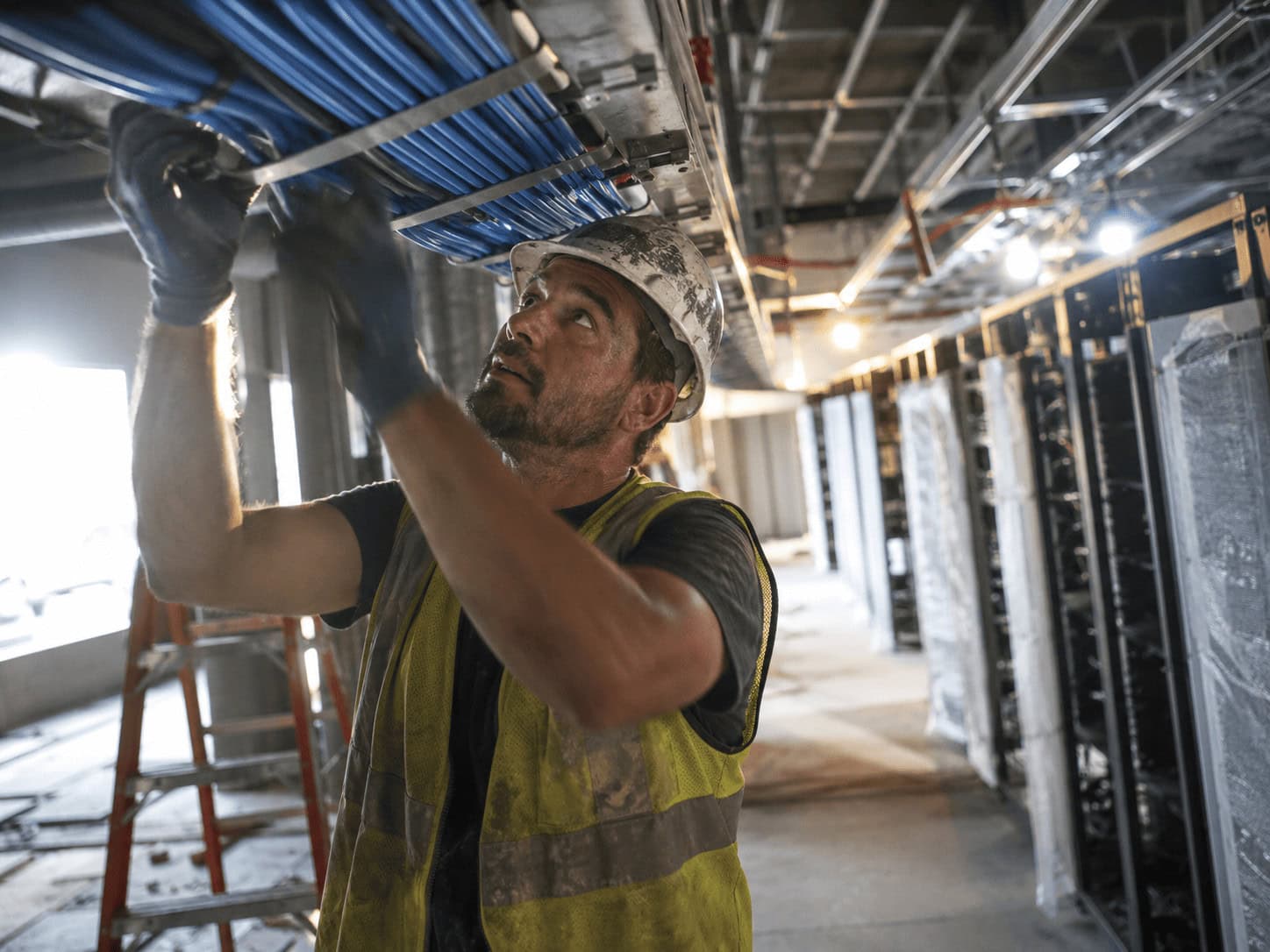 Skilled trade worker installing network cables in a data center for AI infrastructure