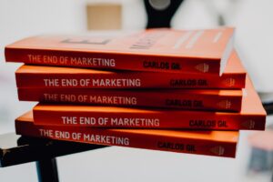 Pila de cuatro ejemplares de 'El fin del marketing' de Carlos Gil sobre una superficie negra.