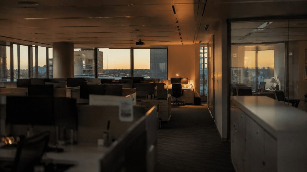 Mostly empty corporate office with a single occupied desk, illustrating return-to-office mandates.