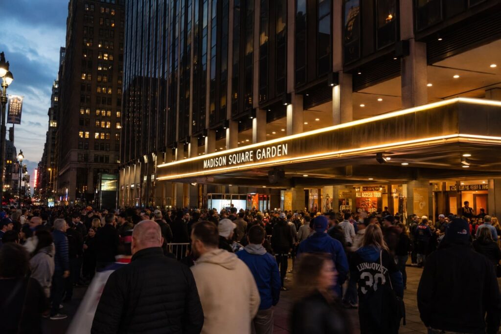 Crowds of fans gather outside an illuminated Madison Square Garden in New York at dusk during the 2026 NBA Finals.
