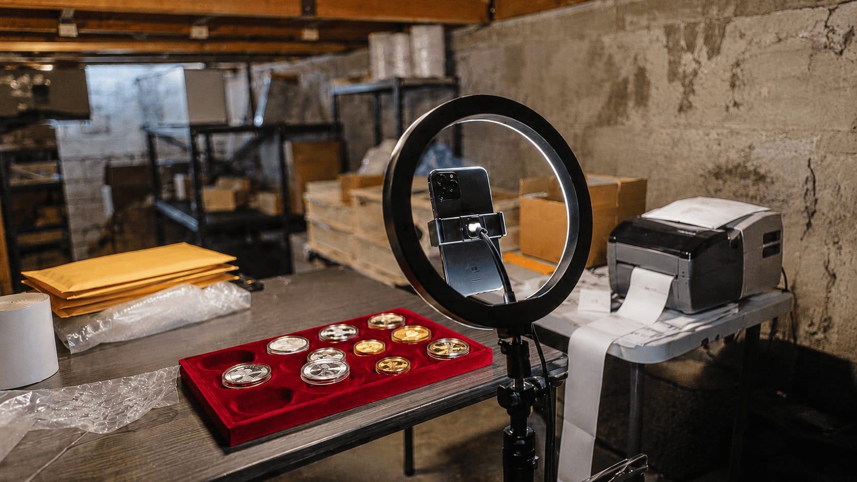 Basement livestream setup with collectible silver and gold coins on a velvet tray under a ring light, used by a top Whatnot coin seller