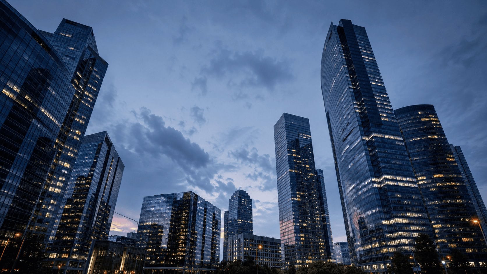 Glass skyscrapers at dusk in a financial district, illustrating the corporate scale driving the 2026 AI deal boom