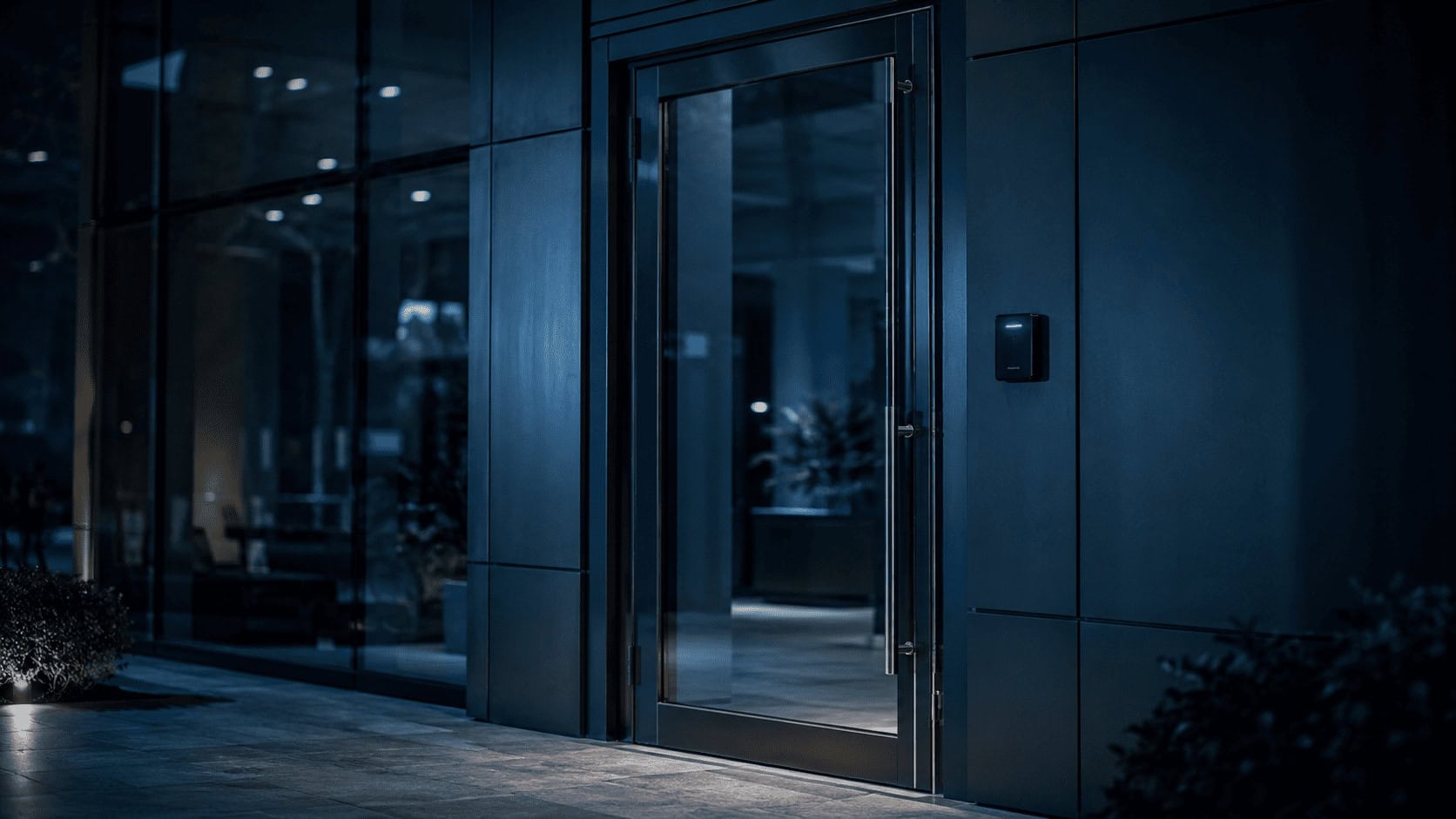 Corporate security badge reader beside a glass office door at night