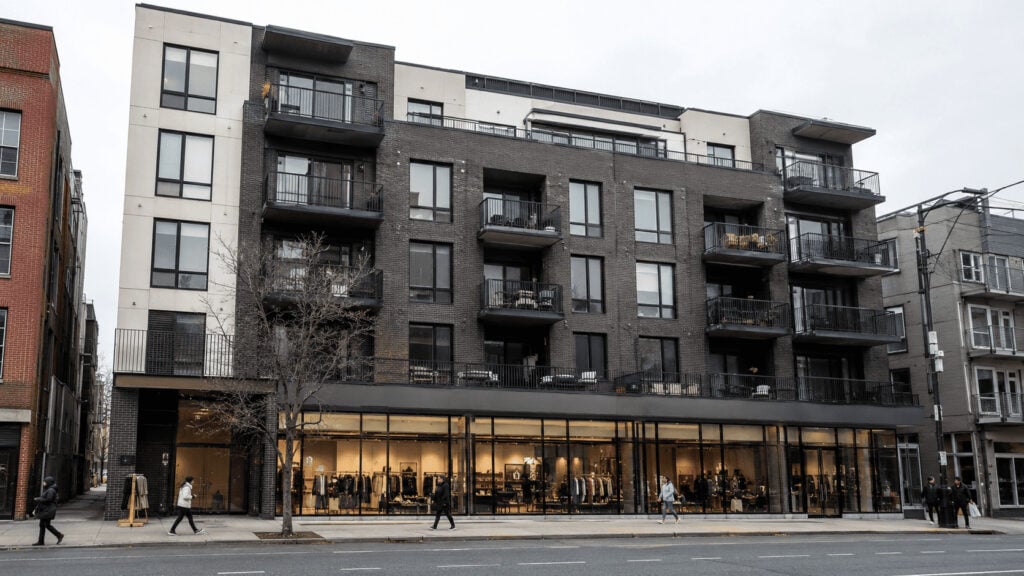 Mid-rise urban apartment building with a large ground-floor retail store, illustrating big-box retailers entering cities through affordable housing developments