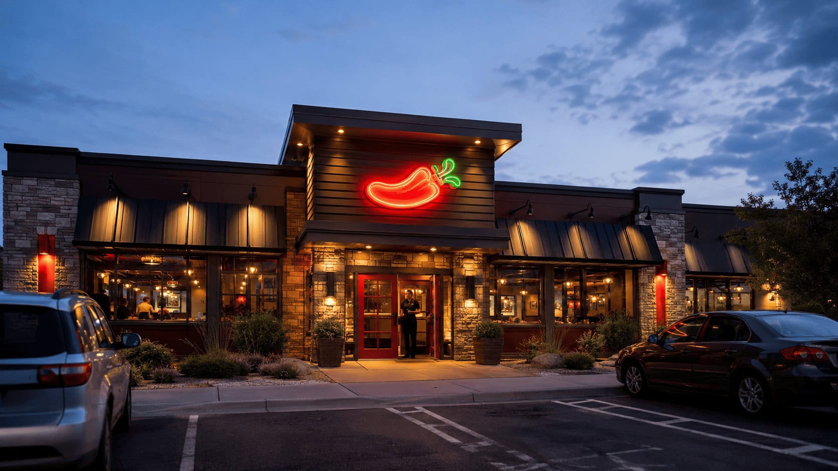 Exterior of a Chili's Grill & Bar restaurant at dusk with the neon chili pepper sign lit