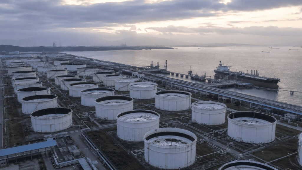 Aerial view of a large crude oil storage tank farm in China with a tanker docked at the coastal terminal