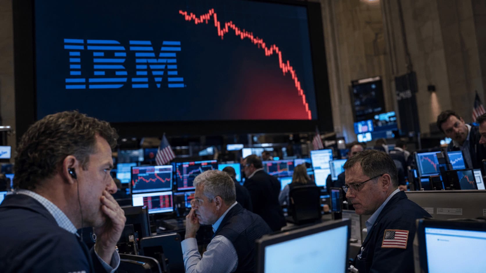 Traders on a trading floor reacting to a large screen showing a plunging IBM stock chart during the 2026 AI market scare.