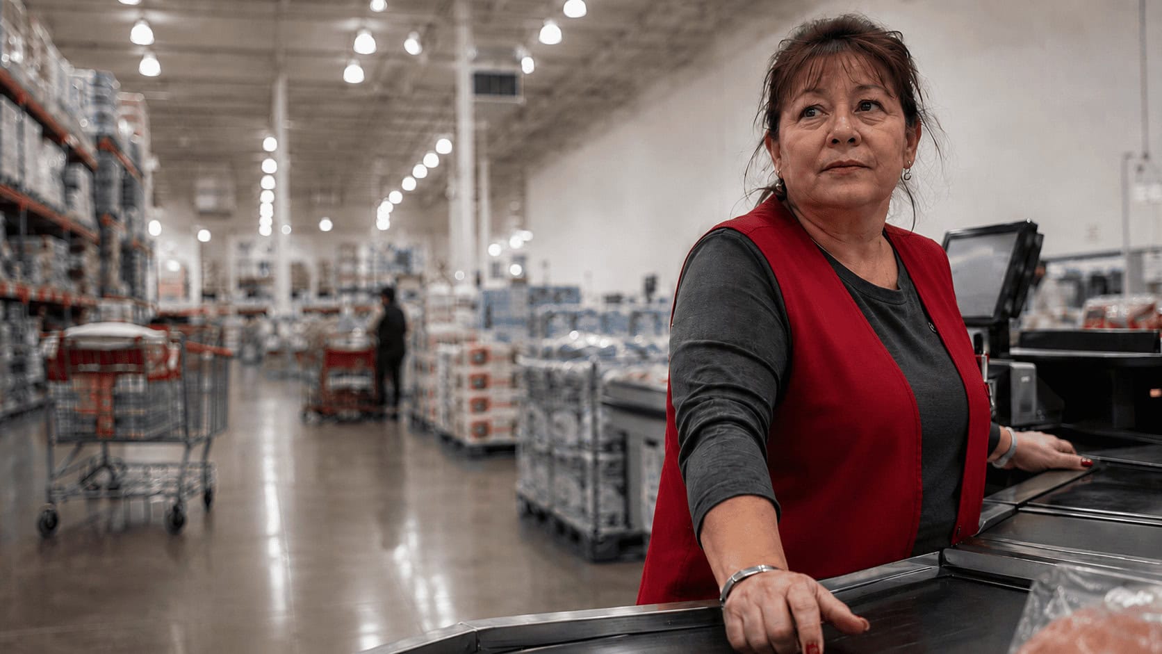 Costco cashier scanning items at a self-checkout register, illustrating the high-wage, low-turnover model behind Costco's success