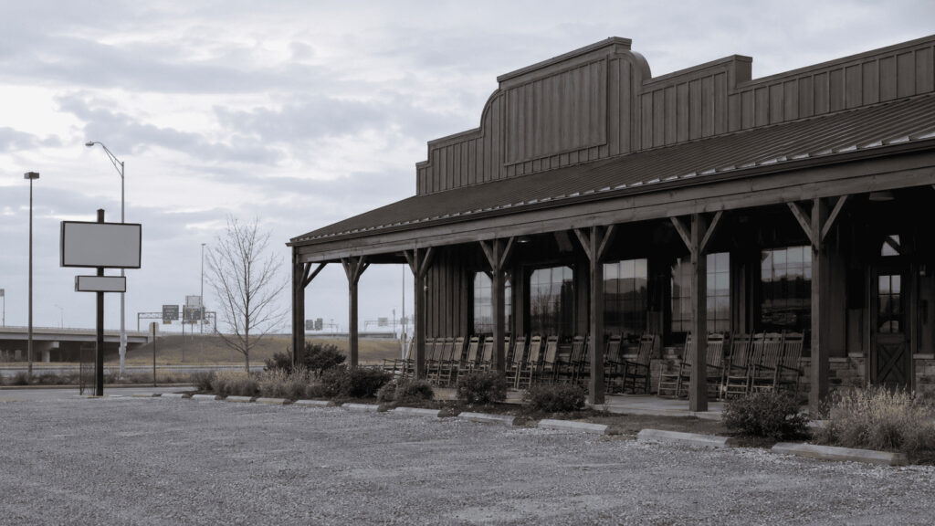Empty rocking chair porch at a country-store restaurant off a highway ramp as Cracker Barrel changes CEOs and sells its real estate