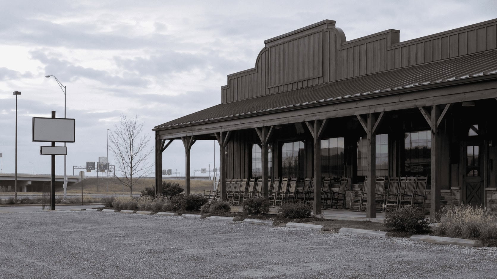 Empty rocking chair porch at a country-store restaurant off a highway ramp as Cracker Barrel changes CEOs and sells its real estate