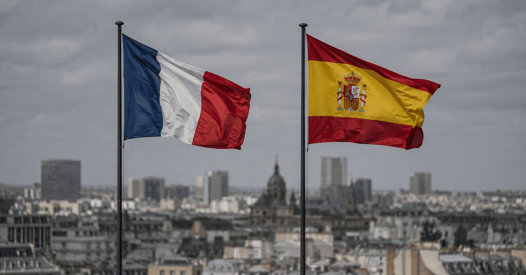 France and Spain flags side by side, representing an economic comparison of the two countries ahead of their 2026 World Cup semifinal.