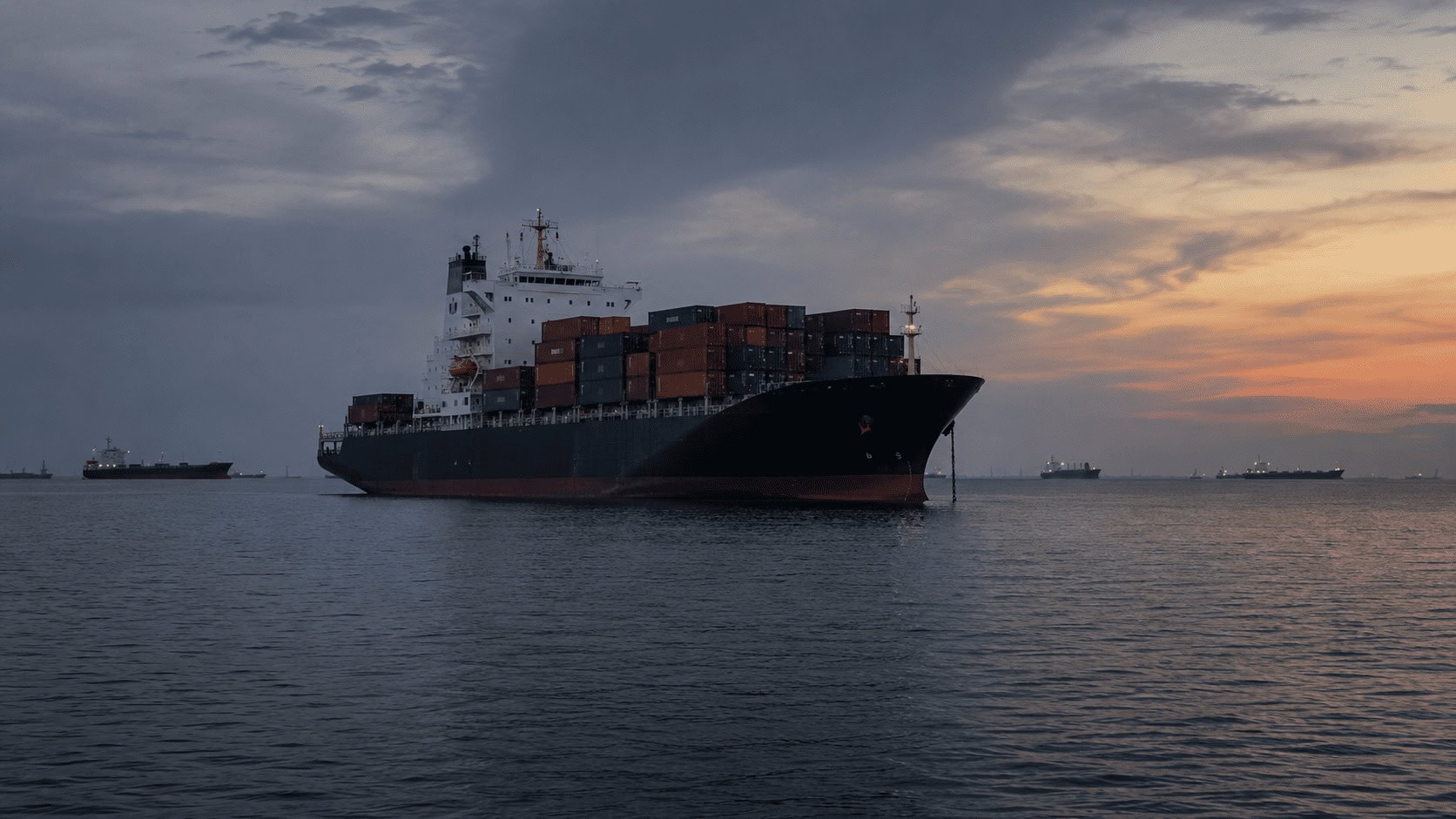 Cargo ships queued outside a Gulf port, illustrating shipping delays from Strait of Hormuz disruptions.
