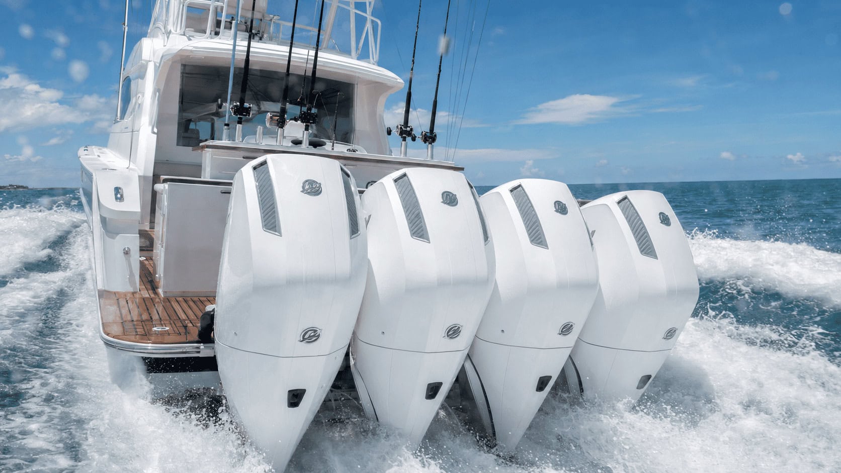 Four white high-horsepower Mercury outboard motors mounted across the transom of a large sportfishing yacht underway offshore