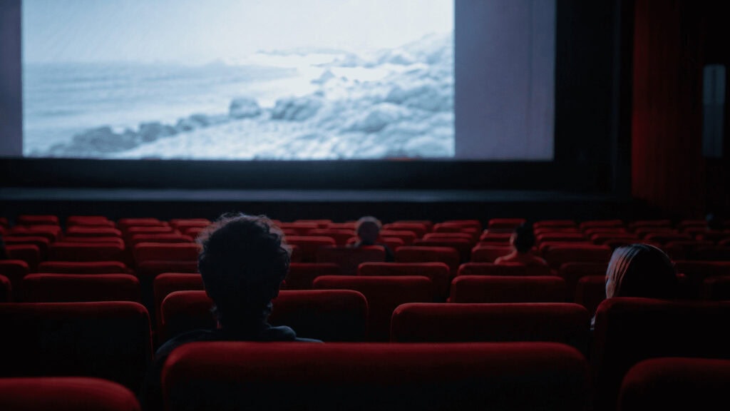 An empty cinema auditorium lit by the glow of a blank screen, illustrating Disney's Moana remake box office flop.