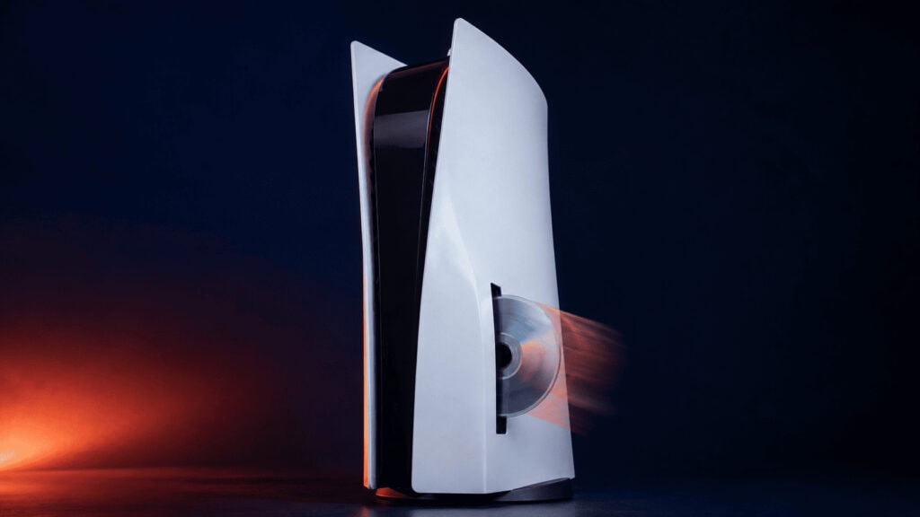 A PlayStation 5 console with a game disc partially ejected from the drive against a dark background.