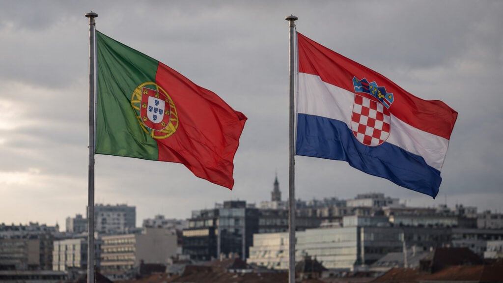 Portugal and Croatia flags flying over cityscape.