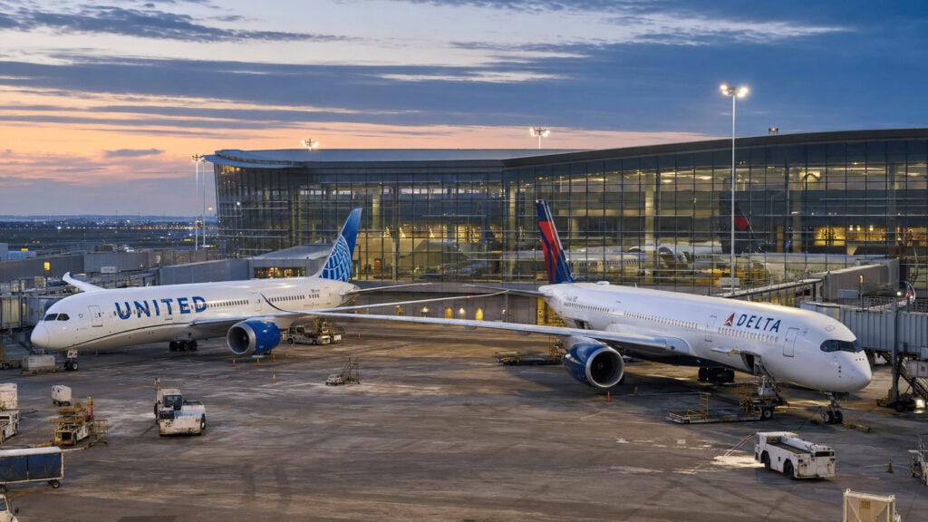 United and Delta aircraft parked at adjacent airport gates at dusk