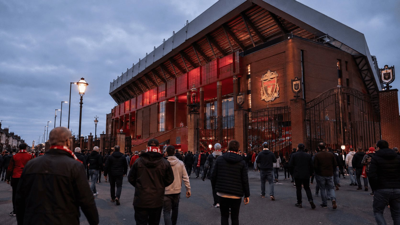 Anfield stadium exterior with the Liverpool FC crest above the Shankly Gates on a matchday evening