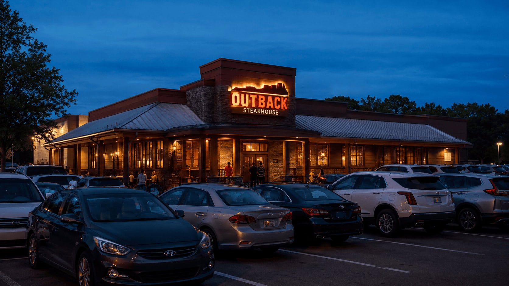 An Outback Steakhouse restaurant lit up at dusk with a full parking lot, evoking Bloomin' Brands' Q2 2026 sales momentum.