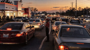 Long line of cars queued at a Chick-fil-A drive-thru spilling onto a suburban road at dusk