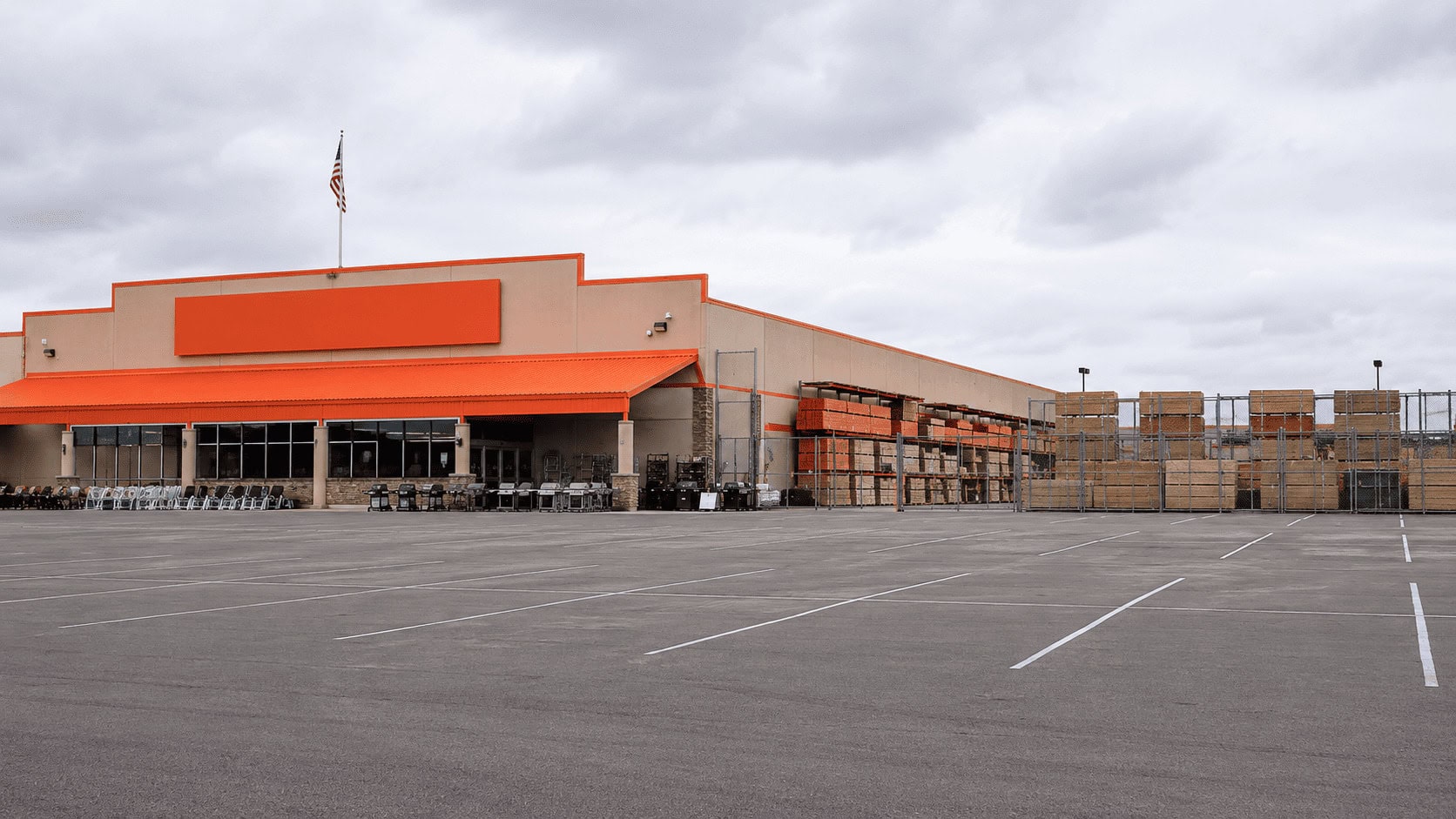 Exterior of a Home Depot store with the orange logo sign, shot in flat daylight against an empty parking lot