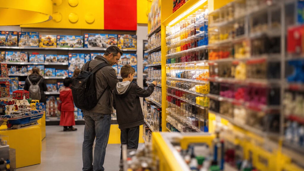 Rows of colourful Lego brick sets on shelves inside a brightly lit Lego branded retail store