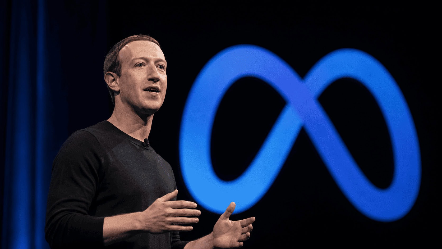 Mark Zuckerberg on stage at a Meta developer event with the Meta logo lit behind him, addressing the company's return to open-weight AI models