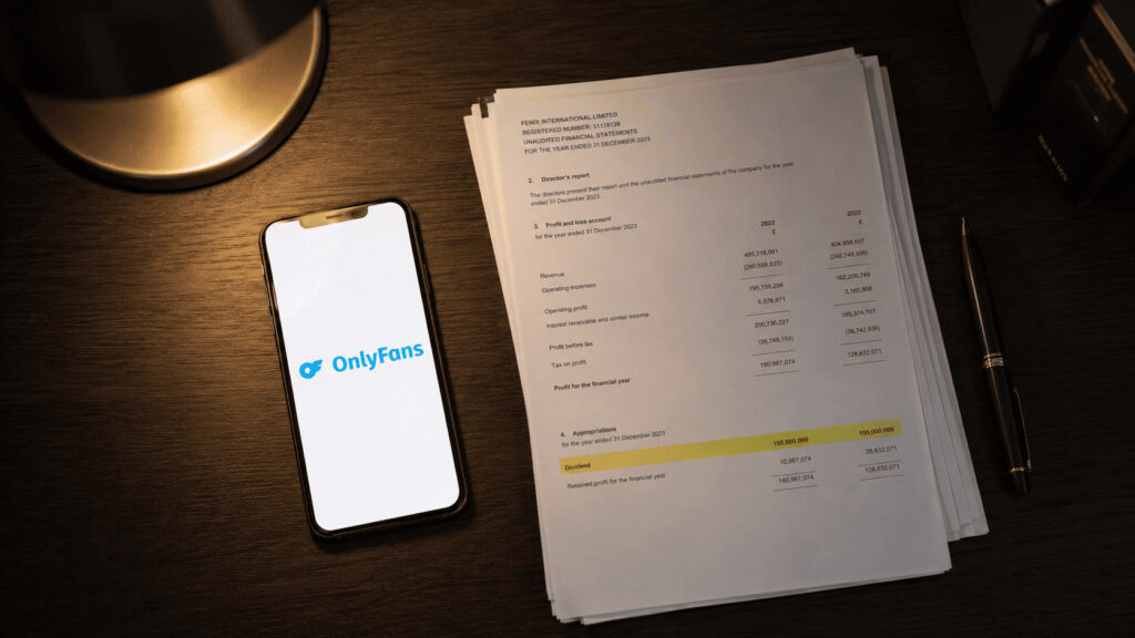 OnlyFans logo glowing on a smartphone screen beside a printed financial statement on a dark desk