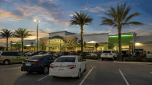 A Publix supermarket storefront lit at dusk with a full parking lot in Florida.