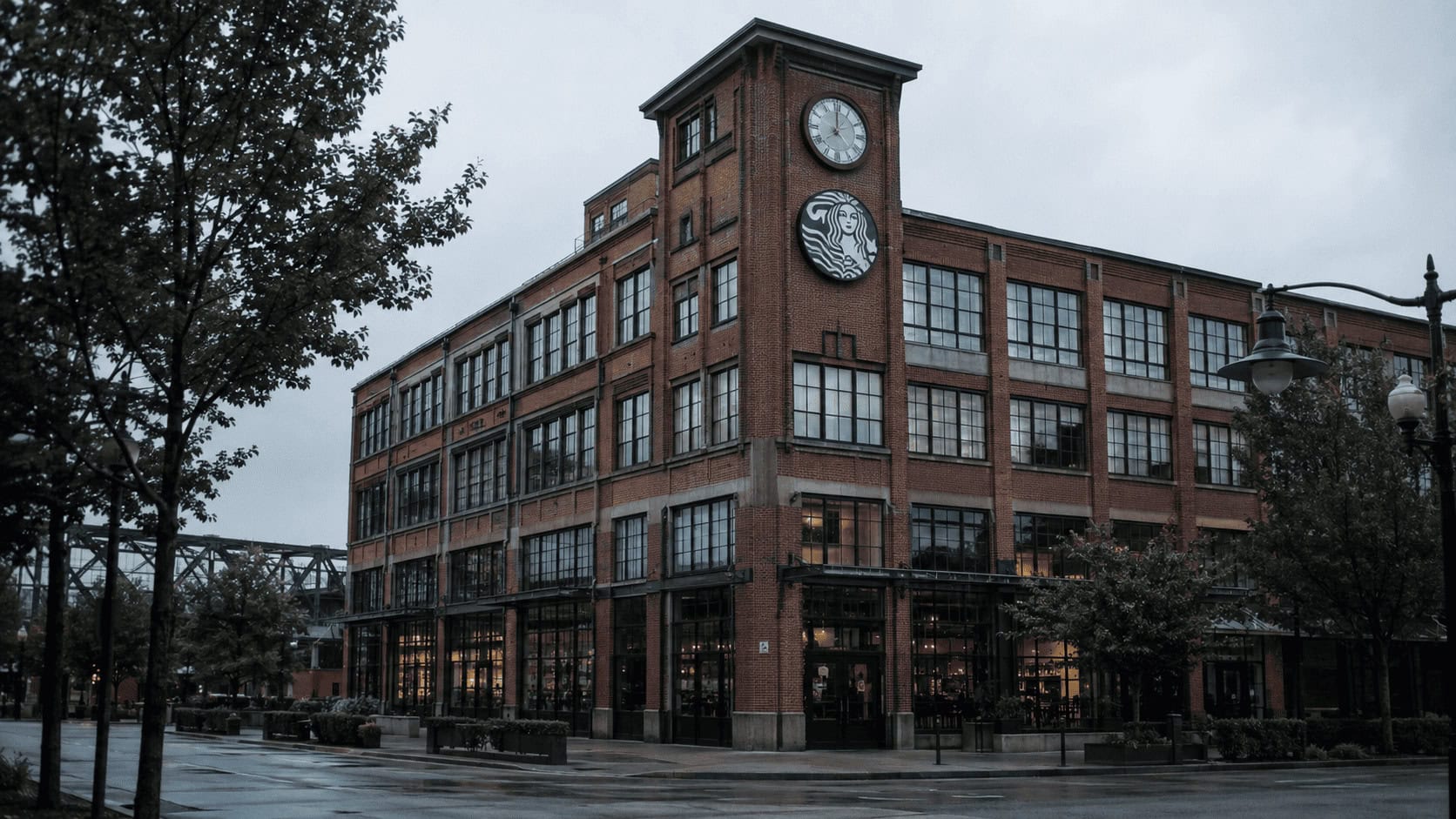 Starbucks Center headquarters building in Seattle's SoDo district under overcast sky, with the Starbucks siren logo visible on the clock tower.