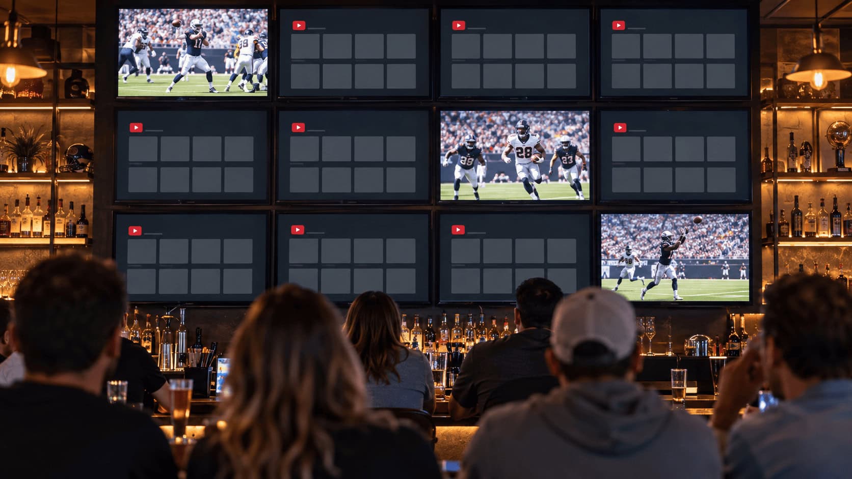Sports bar wall of screens where only a few show live NFL games and the rest display an empty streaming grid, illustrating NFL Sunday Ticket carrying fewer games on YouTube TV.