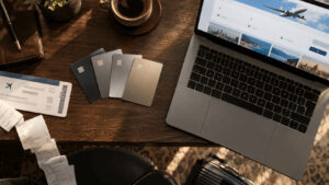 Cuatro tarjetas de crédito metálicas de alta gama estaban dispuestas en abanico sobre un escritorio junto a una computadora portátil y un largo recibo de papel, ilustrando la relación entre la cuota anual y el crédito en el estado de cuenta.