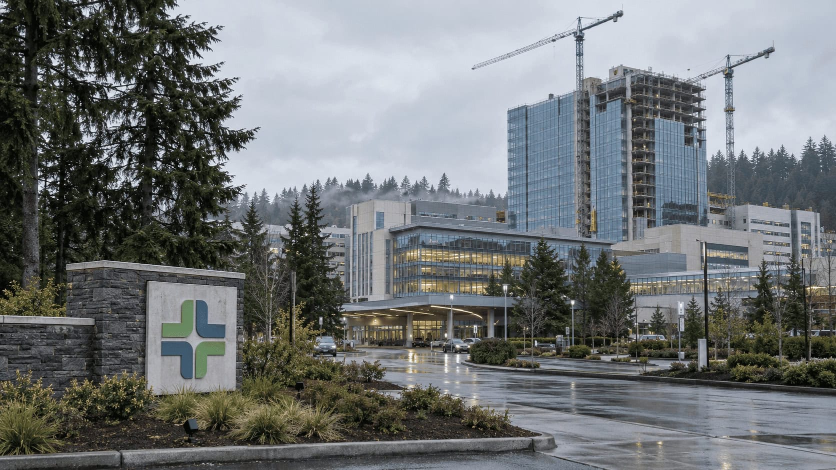Grúas de construcción junto a una nueva torre hospitalaria que se levanta en un campus médico suburbano de Portland bajo un cielo nublado